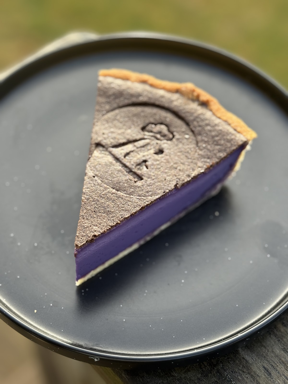 A slice of A's Cafe's signature purple ube custard tart with the logo stamped on top
